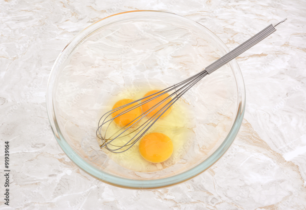 Three eggs in a glass bowl with a whisk Three eggs in a glass bowl with a whisk