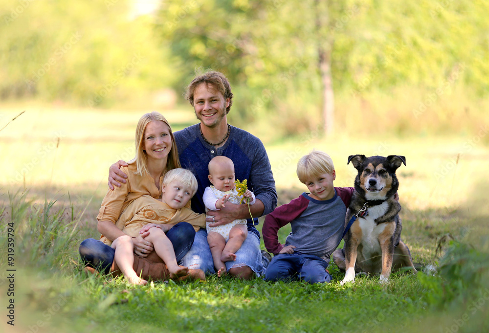 Happy Young Family Relaxing Outside with Pet Dog