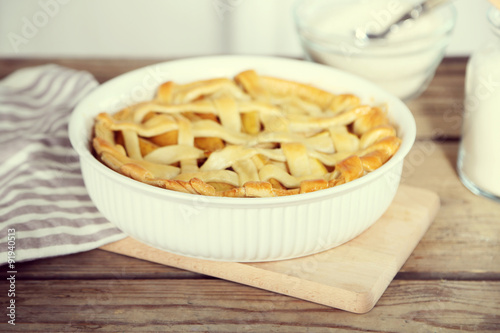 Homemade apple pie on wooden table, on light background