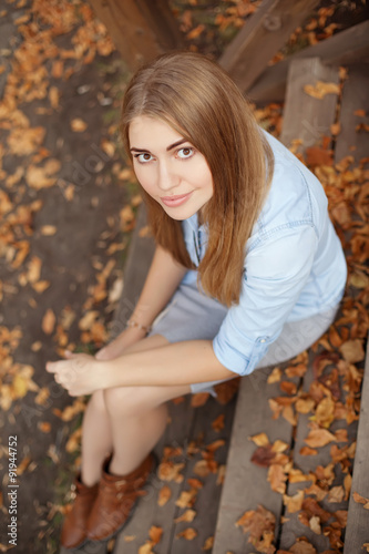 girl sitting on the steps of the wooden porch, autumn season