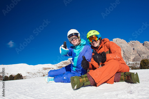 two snowboarders on top of the mountain having fun