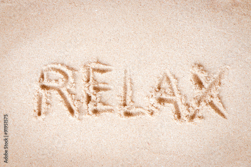 Text "Relax" writing on sand at the beach, Relax concept.