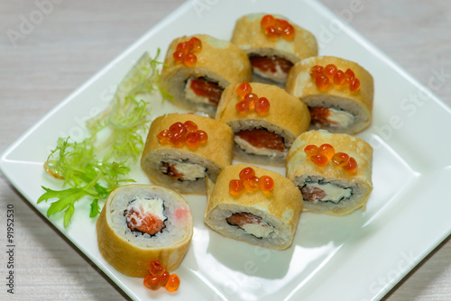 Close-up of a white plate with sushi set - Russian pancakes with