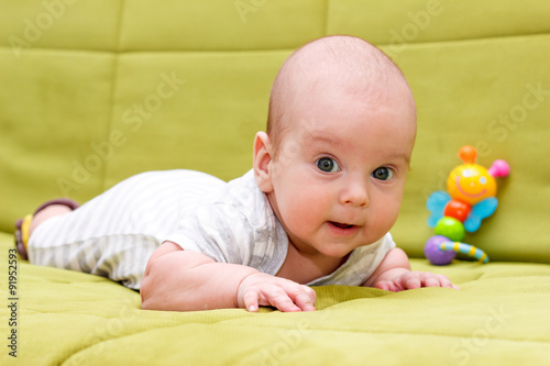 Baby lying on the green couch with toy