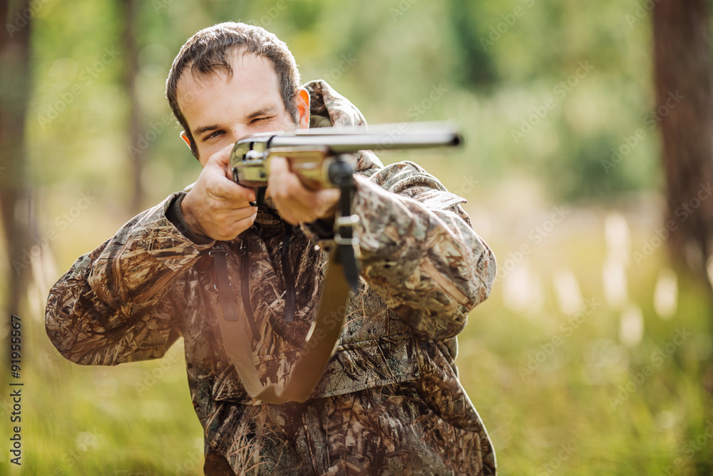 Fototapeta premium hunter with shotgun looking through binoculars in forest