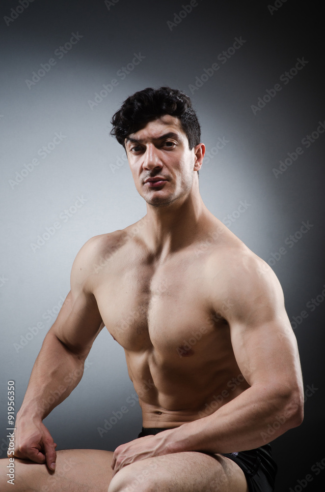 Fototapeta premium Muscular man posing in dark studio