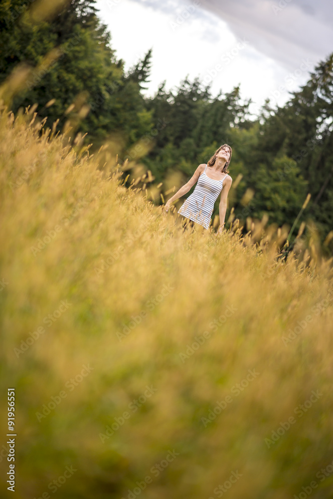 Young woman standing in an autumn meadow looking up in the sky Young woman standing in an autumn meadow looking up in the sky