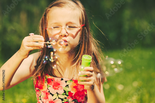 Happy little girl child blowing bubbles outdoor.