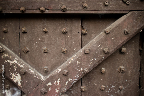 Heavy brown wooden door of a temple in Asia studded with bolts & crossing beams