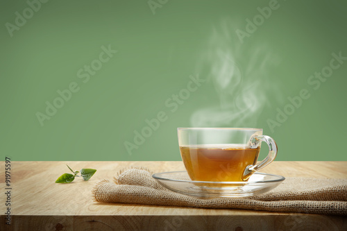 Cup of tea with sacking on the wooden table and green background