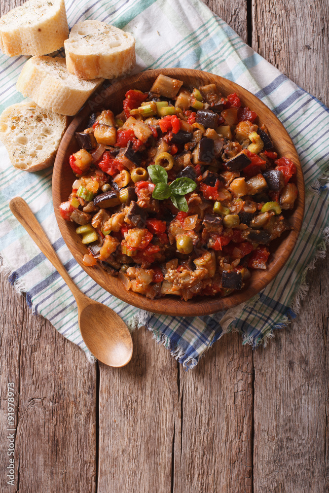 Caponata with aubergines in a wooden plate. vertical top view
Caponata with aubergines in a wooden plate. vertical top view