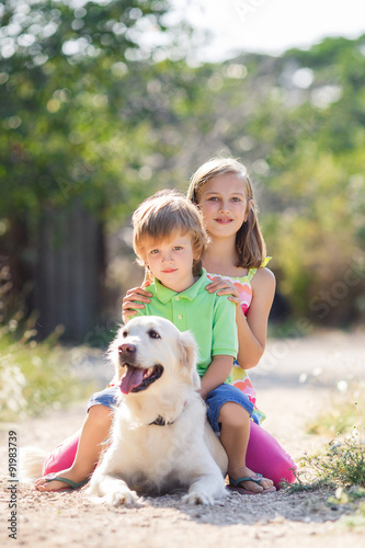 Girl and boy with labrador retriever in summer park