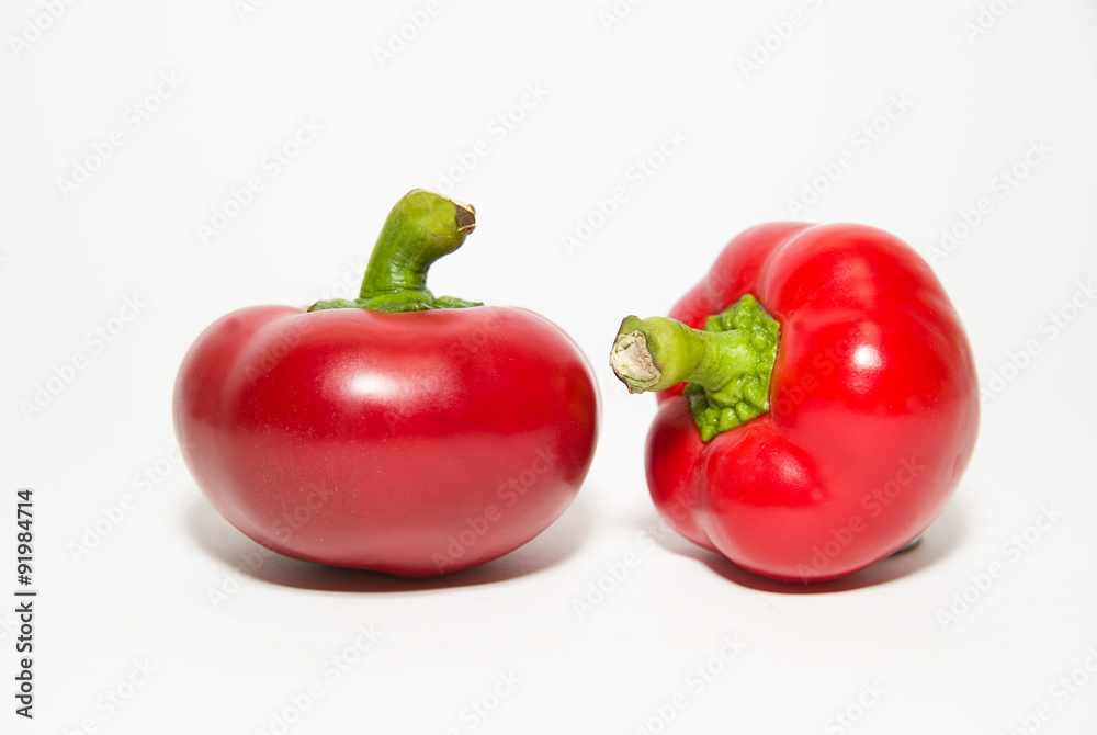 Two ripe red peppers on over white