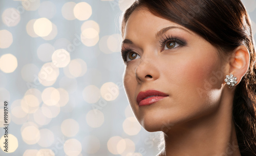 woman with diamond earring over holidays lights