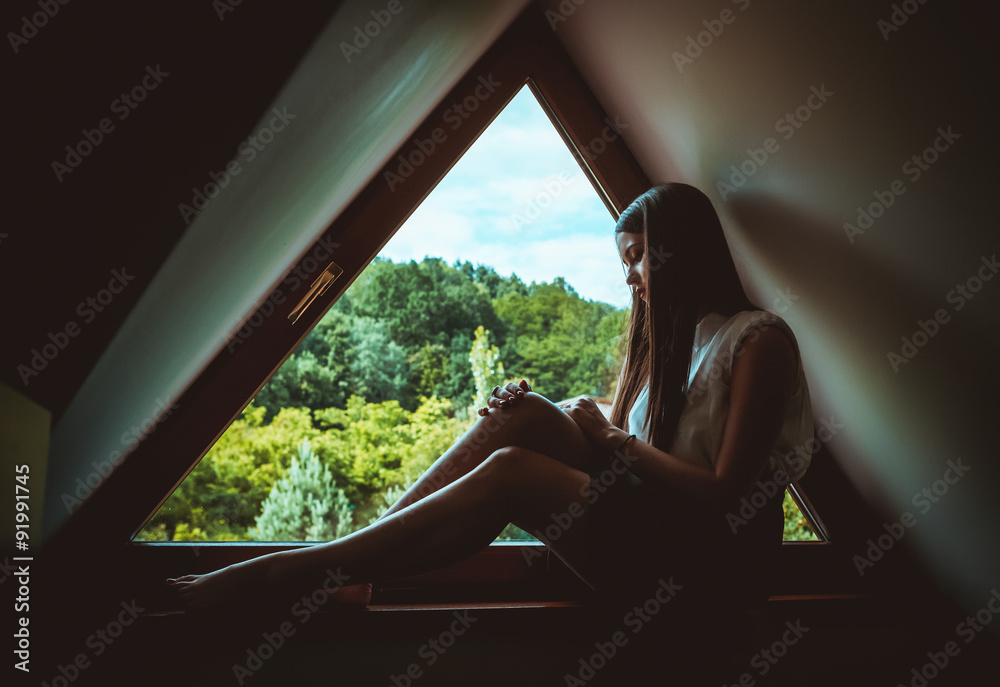 Young lonely woman sitting on a window