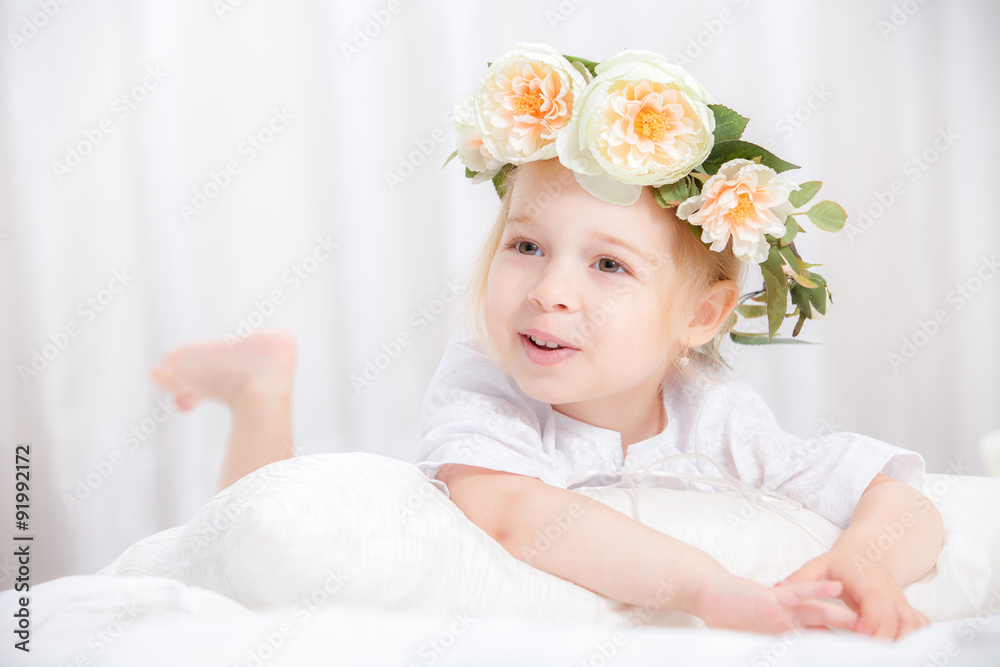 happy little girl with a wreath on the head on a bed happy little girl with a wreath on the head on a bed