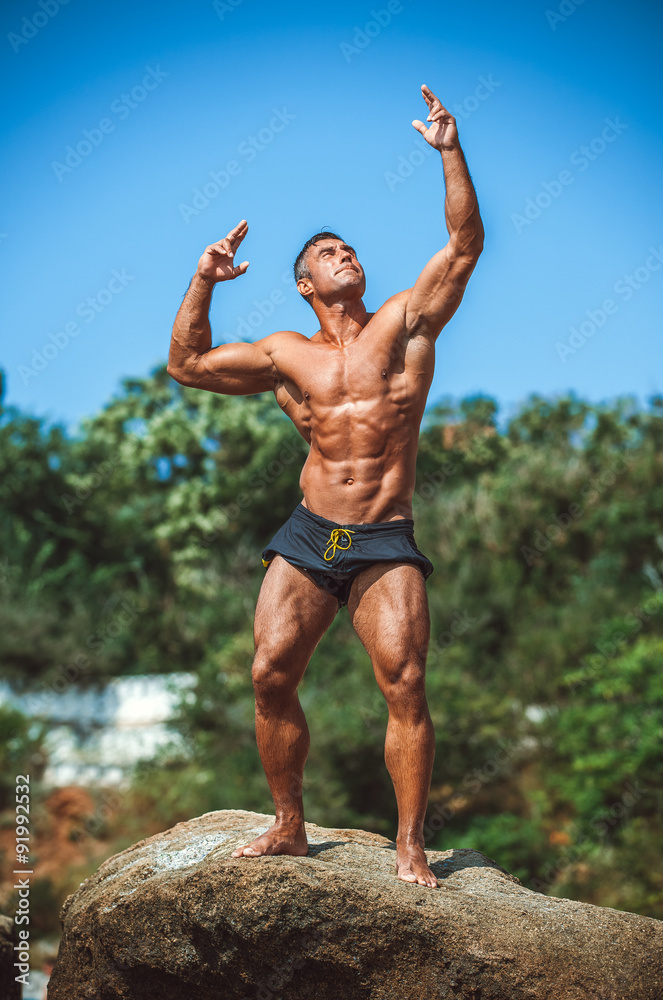 Man Athlete stands on a rock by the sea against the sky Man Athlete stands on a rock by the sea against the sky