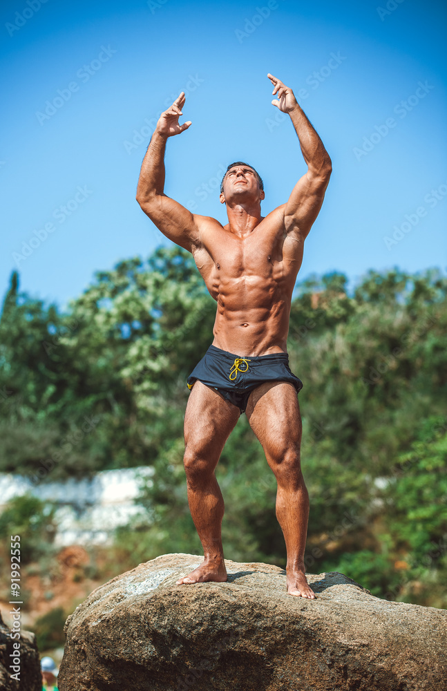 Man Athlete stands on a rock by the sea against the sky Man Athlete stands on a rock by the sea against the sky
