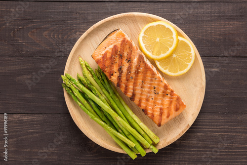 Grilled salmon with lemon, asparagus on the wooden background