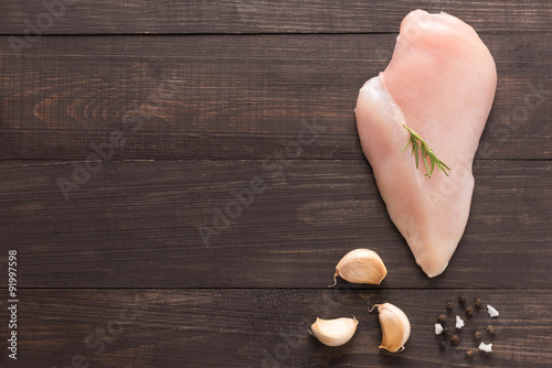 Top view raw chicken breast and garlic, pepper on wooden backgro