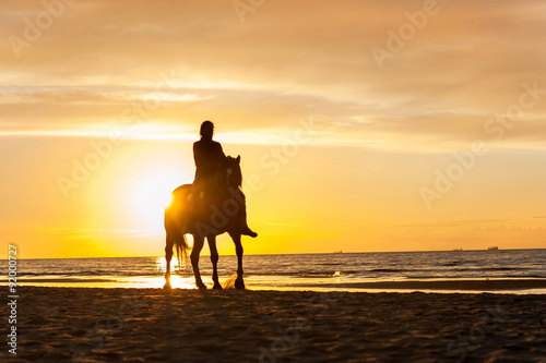 Fototapeta Naklejka Na Ścianę i Meble -  Horseriding at the beach on sunset background. Multicolored outd