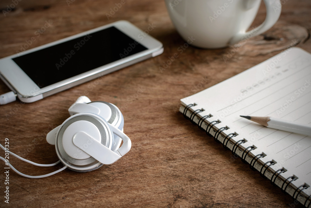 earphone with coffee and notebook on old wooden table earphone with coffee and notebook on old wooden table