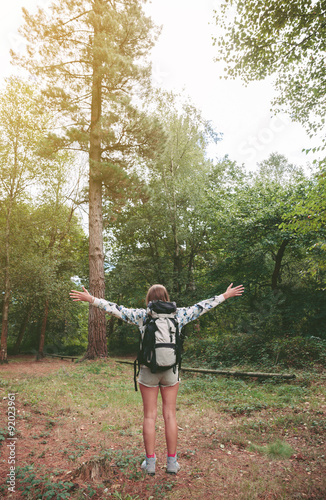 Hiker woman with backpack raising her arms into the forest © David Pereiras