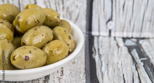Pickled olive in a white bowl over rustic wooden background