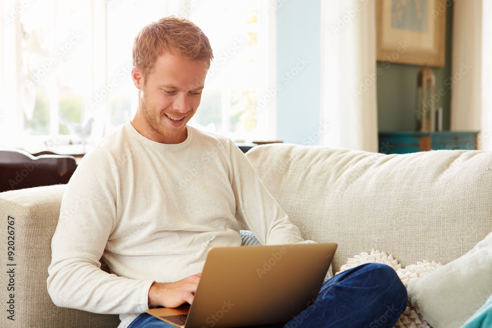 Man Relaxing On Sofa At Home Using Laptop Computer Man Relaxing On Sofa At Home Using Laptop Computer