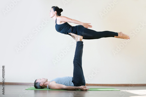 Man and woman doing acro yoga or pair yoga indoor photo