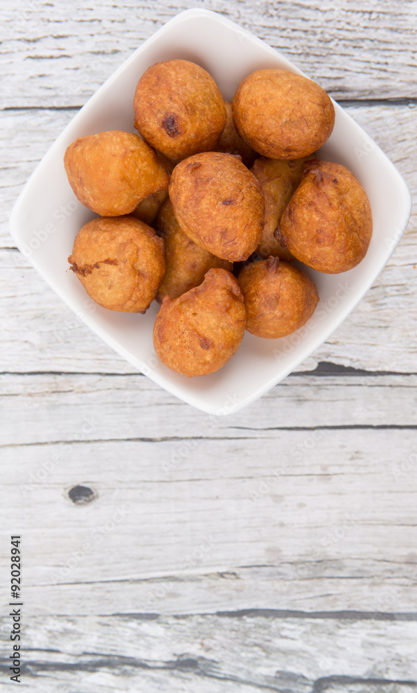 Popular Malaysian fritter snack deep fried banana balls or locally known as Cekodok Pisang in white bowl