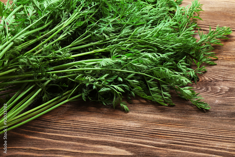 Green tops of organic carrots on wooden table, closeup Green tops of organic carrots on wooden table, closeup