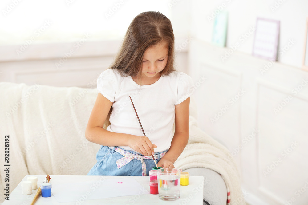 Cute little girl painting picture on home interior background Cute little girl painting picture on home interior background