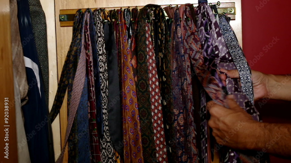 man choosing tie in the wardrobe