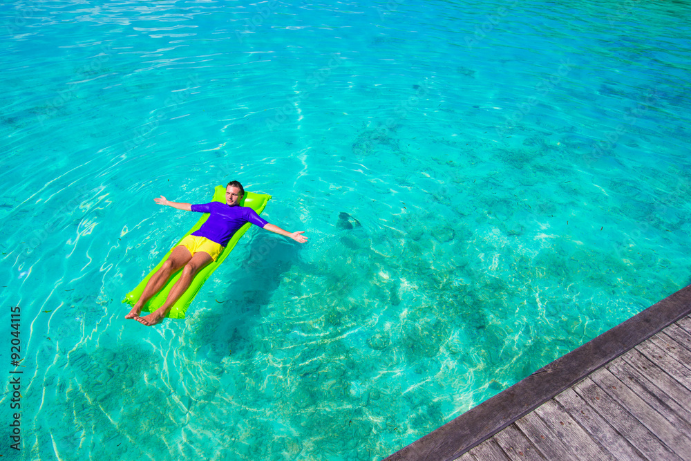 Young happy man relaxing on inflatable mattress in the sea
