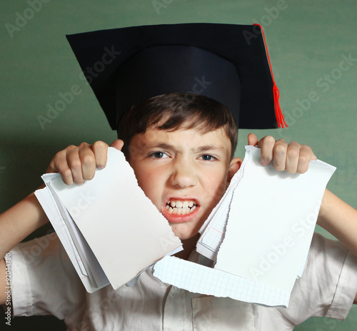 Photos school boy in graduation cap rebel against hard learning