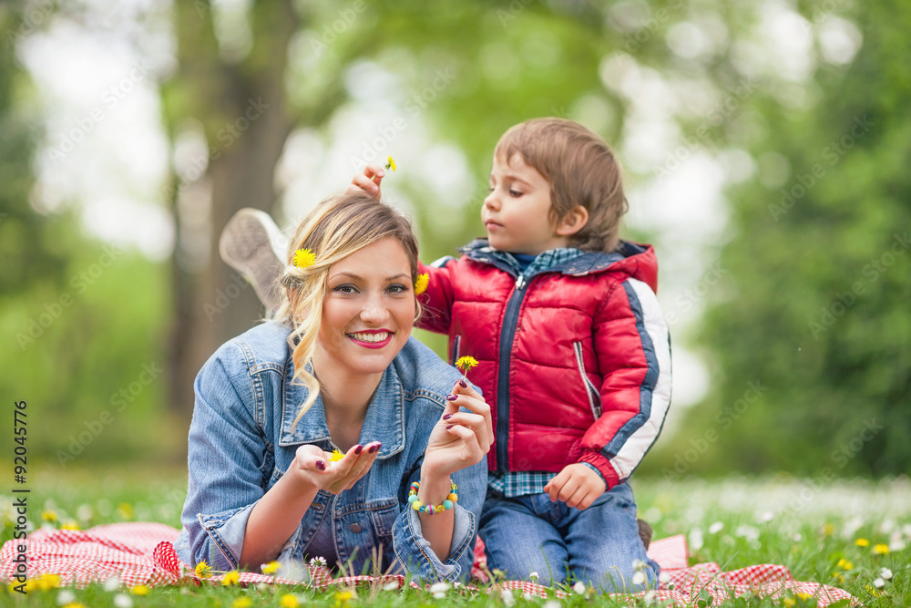 Cute little boy doing his mother's hair in a park Cute little boy doing his mother's hair in a park