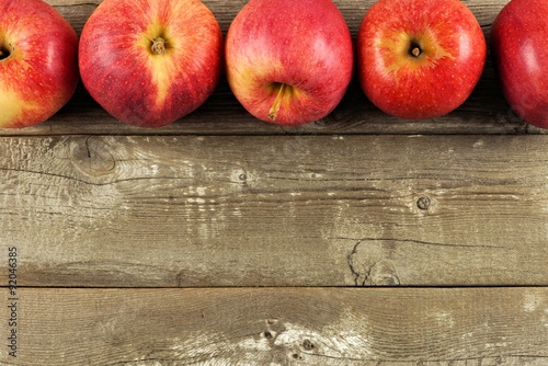 Freshly harvested apples, top border on rustic aged wood background