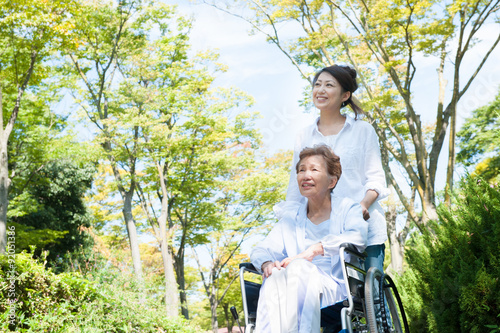 公園の中 車椅子の高齢者と介護する女性 photo
