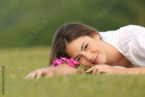 Relaxed woman resting on the green grass with flowers