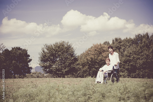 青空の下 車椅子の高齢者と介護する女性