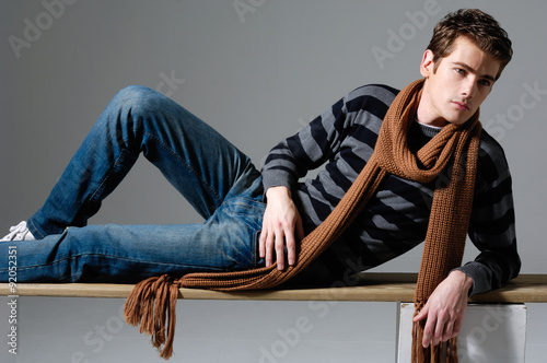 Handsome man in jeans sitting chair over a grey background