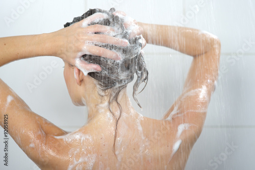 Young woman washing head with shampoo