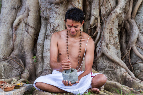 Obraz na plátně A young man preparing ayurvedic medicine in the traditional manner in India