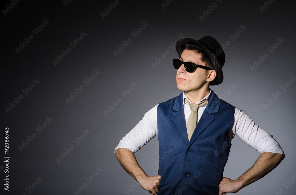 Young man in blue vest and hat against gray Young man in blue vest and hat against gray