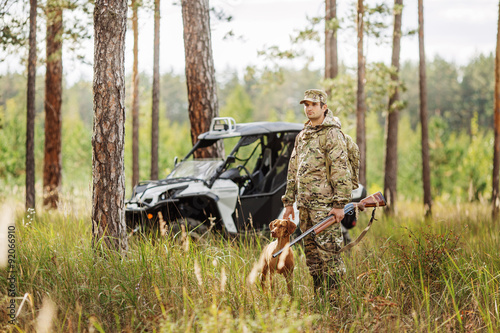 Hunter with Rifle and Four Wheeler Tire in forest