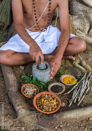 Obraz na plátně A young man preparing ayurvedic medicine in the traditional manner in India