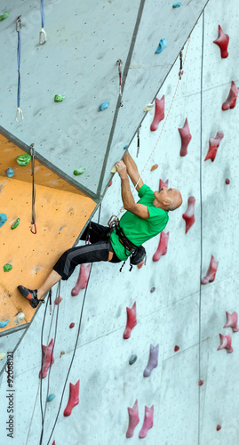 Aged Man Ascends Climbing Wall Elderly male Climber Hanging on Extreme Sport Climbing Wall