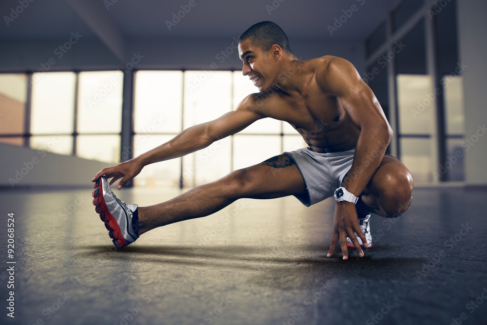 Sports. Man at the gym doing stretching exercises and smiling on