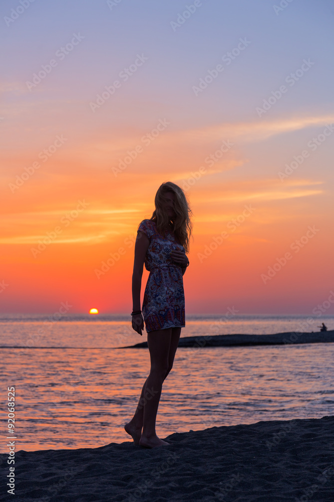 Beautiful young woman on beach at sunset